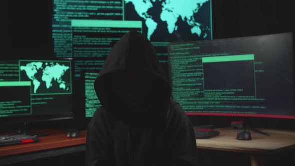 Hacker No Face Pose With Code On Multiple Computer Screens In Dark Room