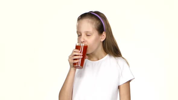 Little Girl Drinks Tomato Juice and Admires It and Shows the Class. White Background