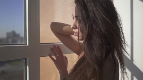 Naked Beautiful Brunette with Long Hair Stand Near Window Inside House