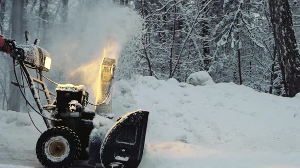 Snowcovered Man Cleans the Road in Winter with Blower Snow Removal Equipment