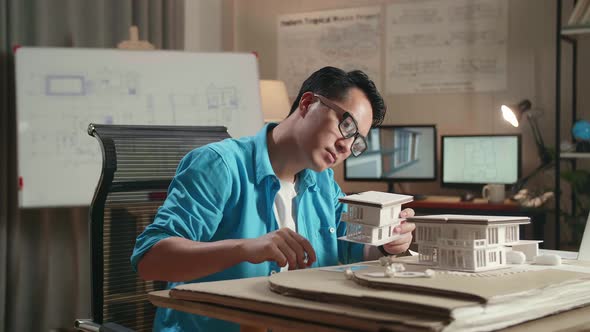 Asian Man Engineer With A Laptop Making Paper Model Of House At The Office