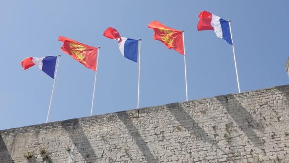 CAEN, FRANCE - JULY 2016 Flags of France and Normandy in city center castle waving  on wind by the d