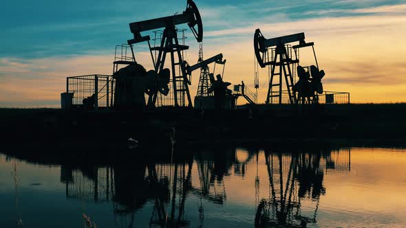 Wide Shot of Oil Pumpjacks and Engineer at Sunset