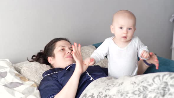 Mother Plays with Her Baby at Home on Her Lap