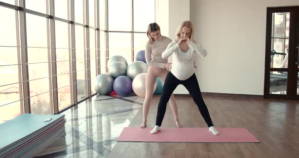 Pregnant Woman and Her Personal Trainer Doing Stretching Exercises