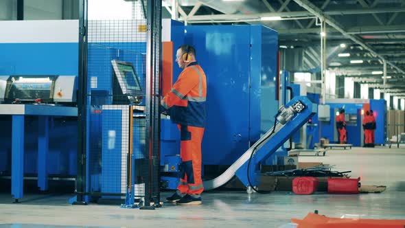 Factory Worker Operating an Industrial Machine on a Modern Assembly Line