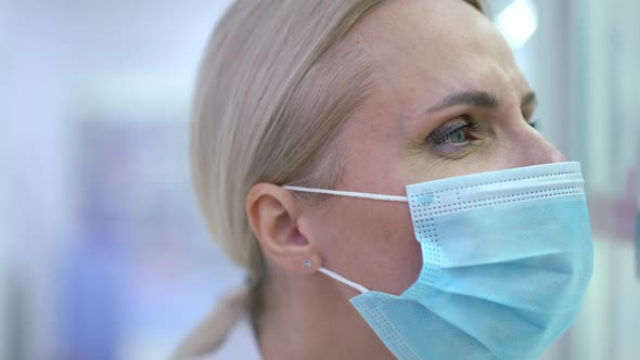 Closeup Face of Concentrated Female Doctor in Coronavirus Face Mask Looking Away Searching Pills