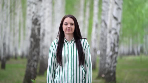 Portrait of a Beautiful Girl on a Background of a Birch Grove in Spring.