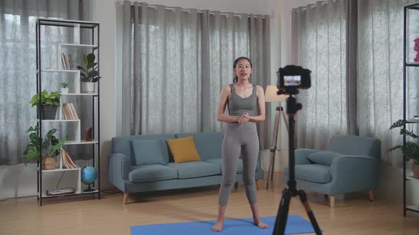 Asian Trainer Female Waving Hand And Speaking To Camera While Recording Teaching Exercise At Home