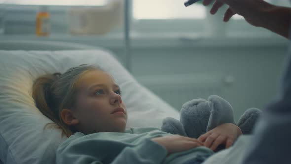 Physician Examining Little Patient with Flashlight Test in Hospital Closeup