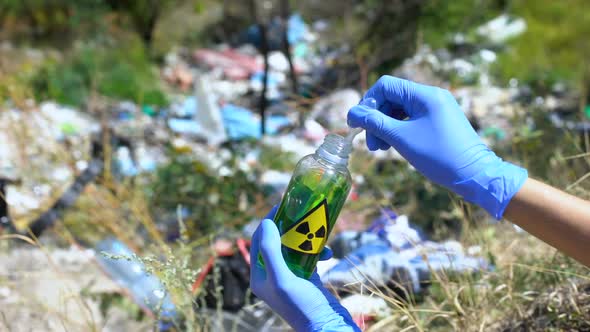 Scientist Taking Sample From Bottle With Radiation Sign Against Open Dumping