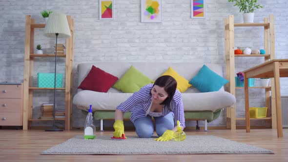 Young Woman in Gloves with Discontent Cleans the Carpet with Her Hands