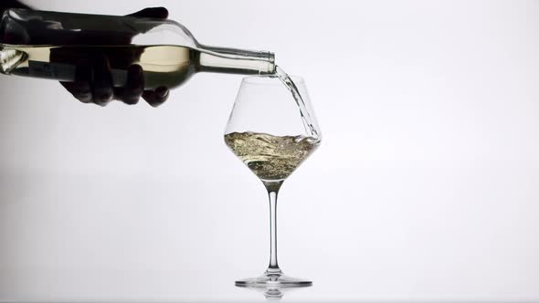 Pouring White Wine From a Clear Glass Into an Glass on a White Background