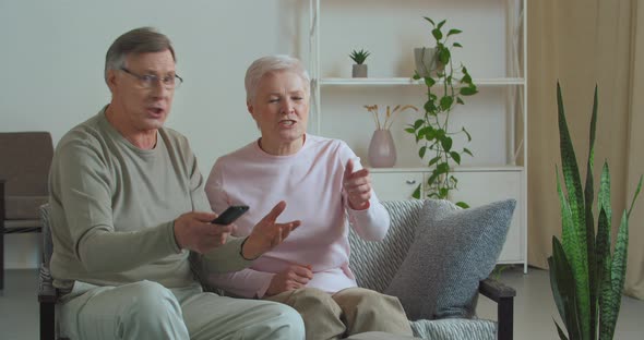 Elderly Couple Rooting Cheering for Sports Team Watching Program Game on TV Loudly Commenting Hope
