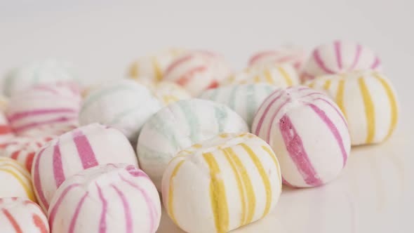 Retro striped round candies on white slow pan 4K video