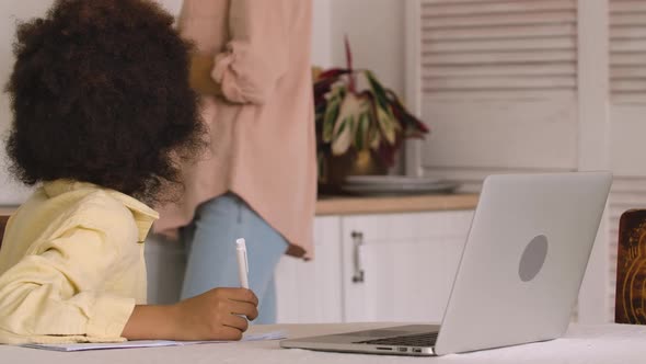 Little Focused Afro American Schoolgirl Studying Remote Online From Home Using Laptop