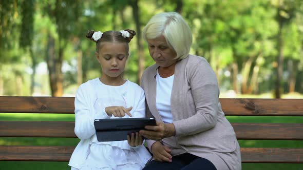 Granddaughter Teaching Granny Using Educational Application on Modern Tablet