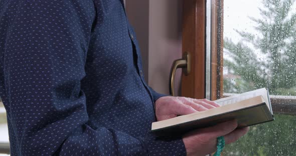 An Old Muslim Man Reading Koran at Home