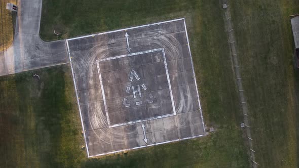 Aerial top down shot of empty heliport or helipad on field during daytime - orbit and landing