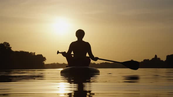 Female Silhouette on SUP Board at Sunset