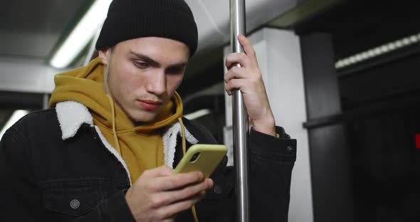 Crop View of Young Man Using His Modern Moilephone While Going on Subway. Handsome Male Student
