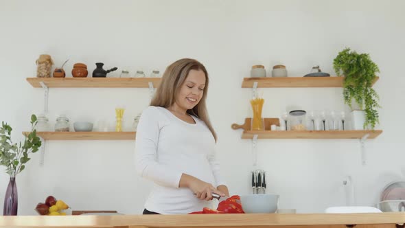 Pregnant Woman in the Kitchen Cuts Red Pepper