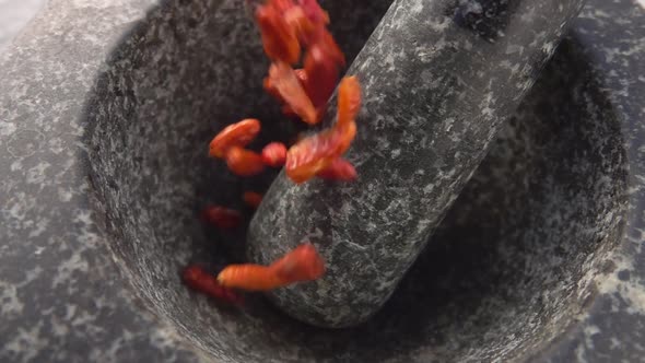 Red Cayenne Pepper Pods Are Falling Into the Stone Mortar