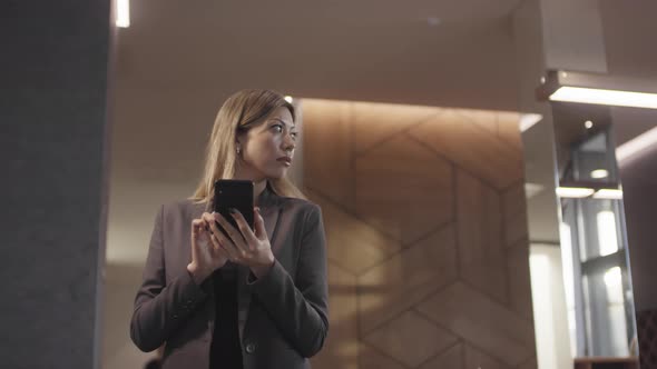 Businesswoman in Mobile Phone in Hotel Lobby