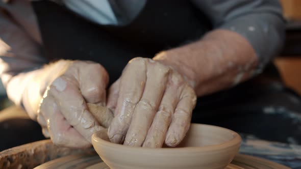 Close-up of Old Master's Hands Making Beautiful Bowl on Spinning Wheel in Workshop