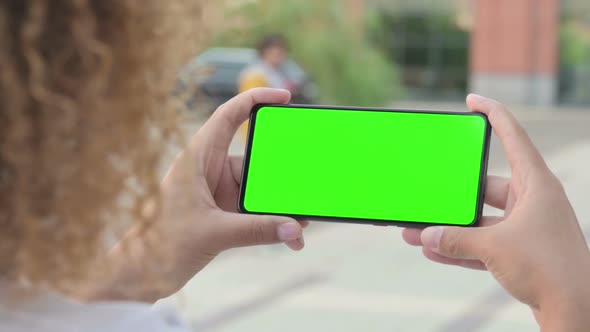 African Woman Looking at Smartphone with Green Chroma Screen