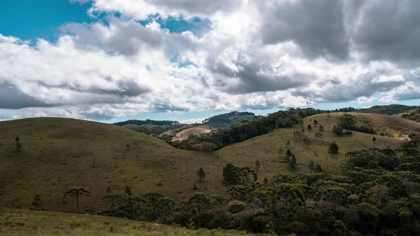 Wide shot timelapse of clouds moving in green landscape alt