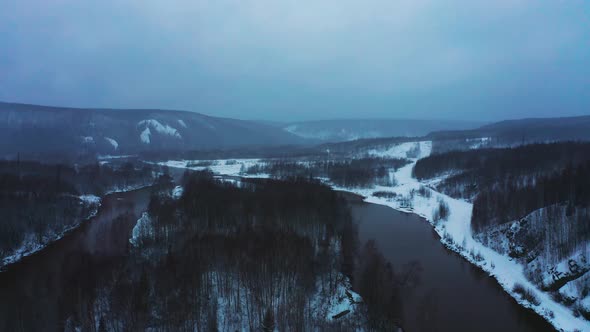 Aerial View of the River with Hills and Snow Forest on the Banks