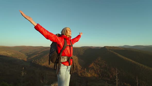 Slow Motion Hipster Millennial Young Woman in Red Jacket with Backpack Stands on Top of Mountain