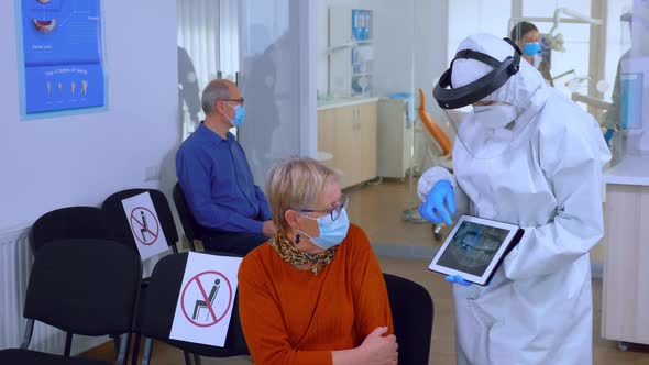 Dentist Doctor with Face Shield Pointing on Tablet Display