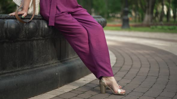 Legs of Unrecognizable Woman Sitting on Fountain Tapping Foot in Slow Motion