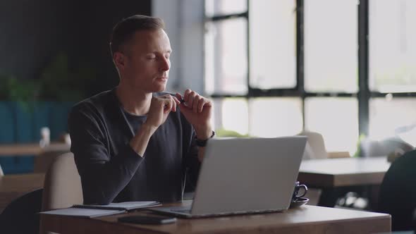 Thoughtful Serious Young Man Student Writer Sit at Home Office Desk with Laptop Thinking of