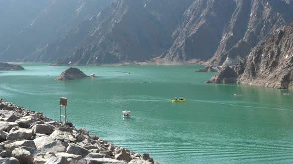 Tourists in colourful pedal boats in the emerald water, Hatta Dam Lake