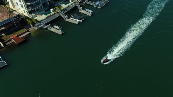 Jet ski rider cruising past luxury homes in a Gold Coast canal at Beautiful Surfers Paradise Austral