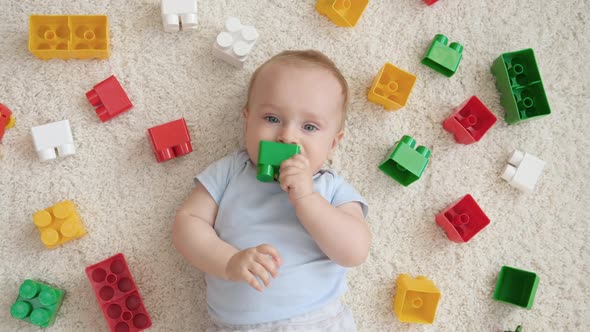 Portrait of Little Baby Boy Chewing and Biting Colorful Toys While Hes Teeth is Growing