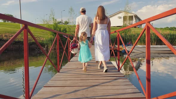 Family Walking on the Bridge Over the River for a Picnic