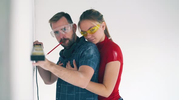 Man with Girlfriend Checks Level of Wall in Room at Renewal