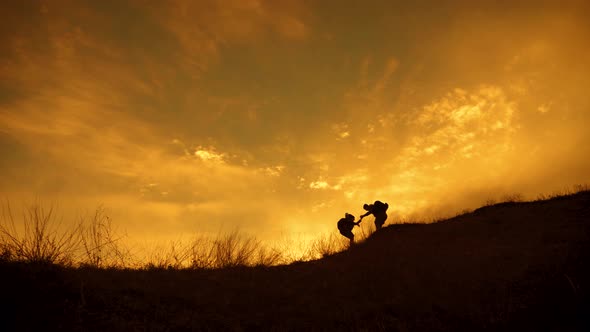 Silhouette of the Team on the Peak of Mountain