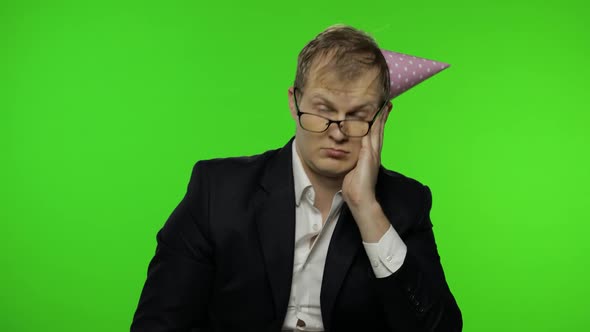 Drunk Sleepy Young Businessman with Hangover in Festive Cap Falling Asleep