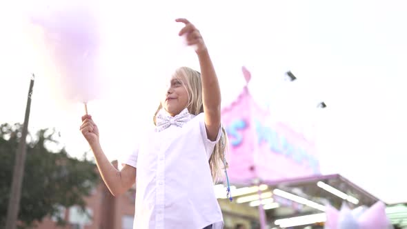 Little girl has fun at the fair with lights and eats sweet cotton.