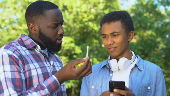 Father Scolding Young Son Phone Showing Marijuana Weed, Bad Habits Prevention