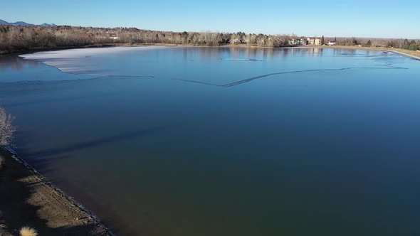 A bird-like flight over a freezing lake west of Denver  captures a sun soaked fall day