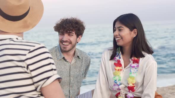 Young Latin American Woman Together with Happy Friends Sitting on the Sand Toasting Beer Bottle