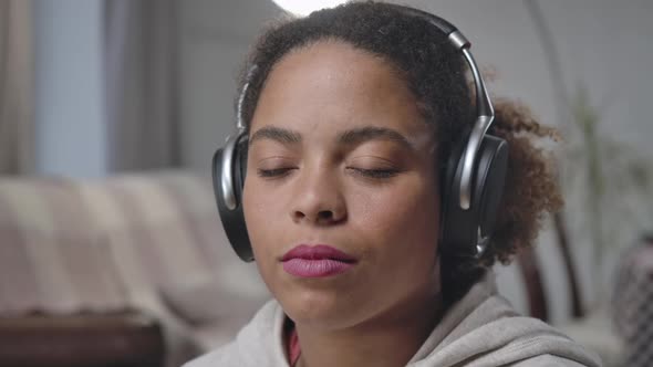 Gorgeous African American Young Woman in Headphones Opening Eyes Winking Looking at Camera