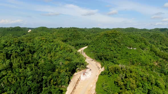 Clearing forest landscape to build new winding road in Indonesia, aerial view