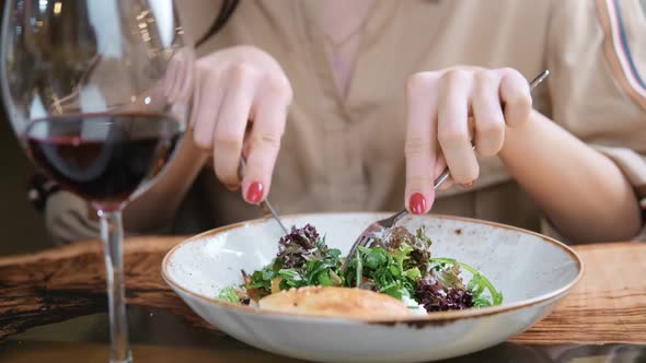 Female Hands Eating Appetizing Food From Plate Using Knife and Fork